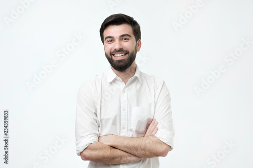 Portrait of smiling handsome man in white shirt standing with crossed arms