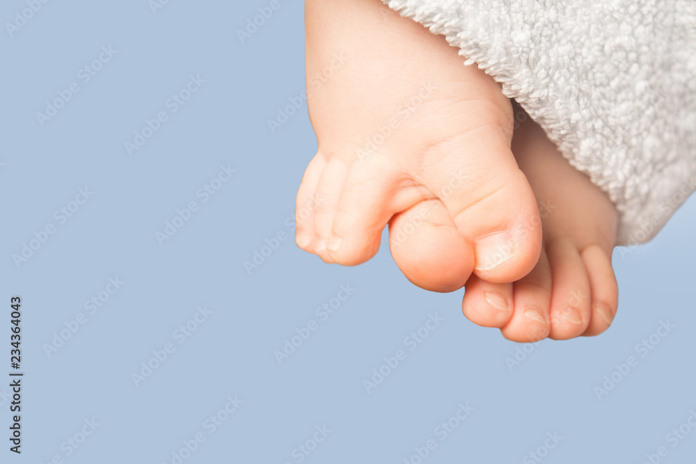 Smal baby feet with blue terry towel on blue background Smal baby feet with blue terry towel on blue background