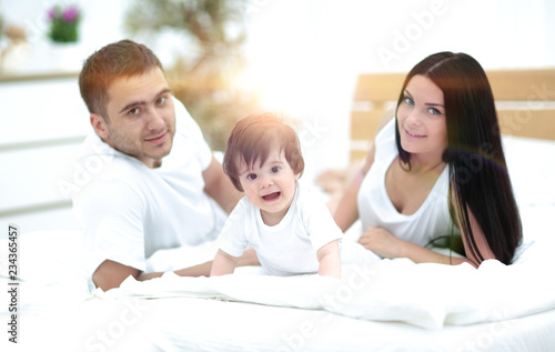 Portrait of happy young family lying in bed together