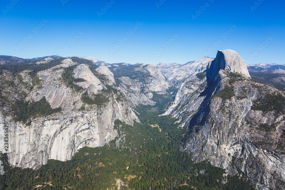 Panoramic summer view of Yosemite valley with Half Dome mountain, Tenaya Canyon, Liberty Cap, Vernal Fall and Nevada Fall, seen from Glacier point overlook, Yosemite National Park, California