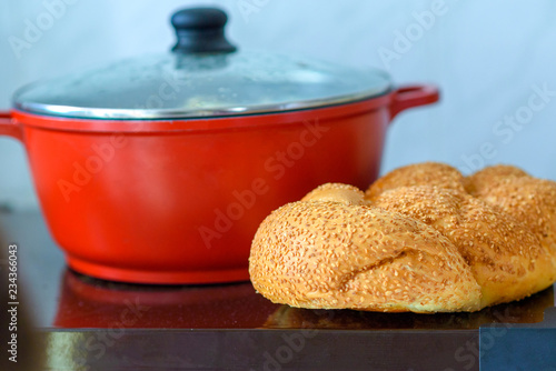 Hot plate for the Sabbath. Pot with traditional food and challah-special bread in Jewish cuisine. Traditional food Jewish Shabbat.
