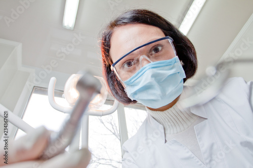 Doctor dentist in mask looks at patient