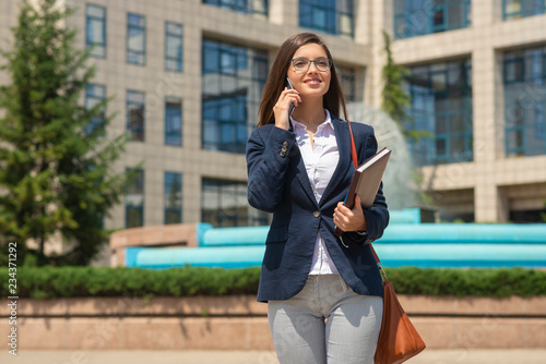 Business woman talking on phone and holding notebook outdoor