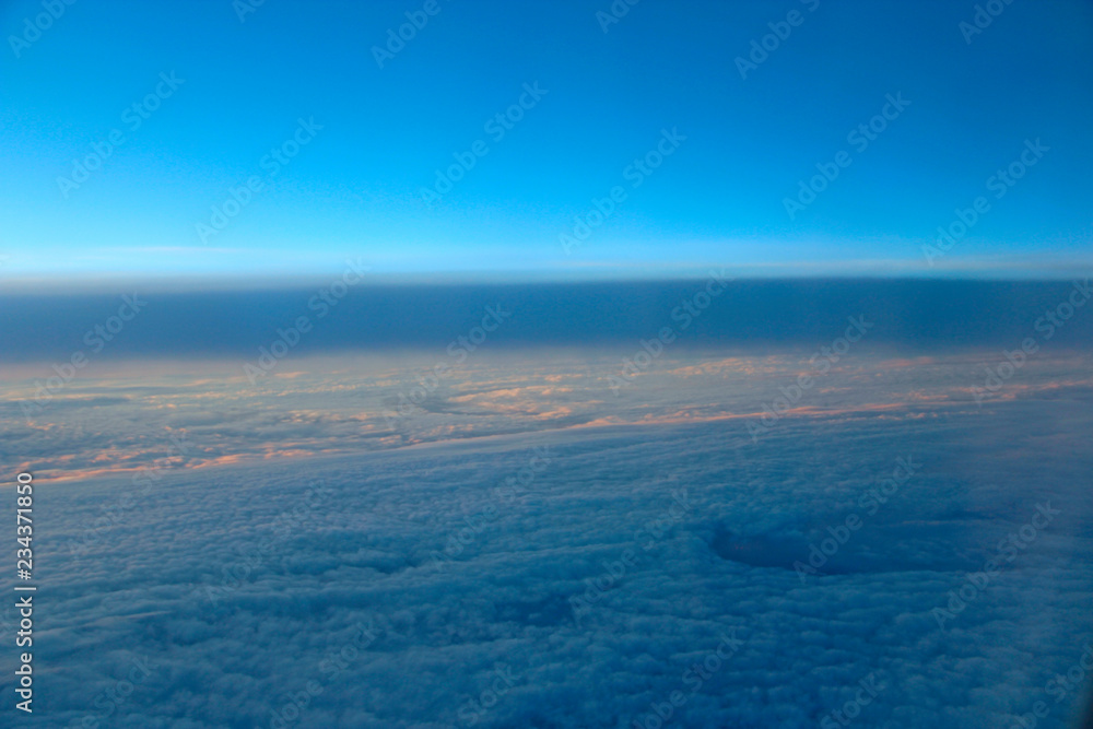 Beautiful panorama from window of plane in morning sun over clouds