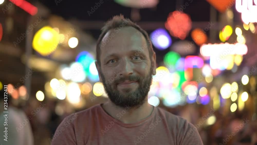 Handsome man standing on the street at night and smiling to the camera Handsome man standing on the street at night and smiling to the camera