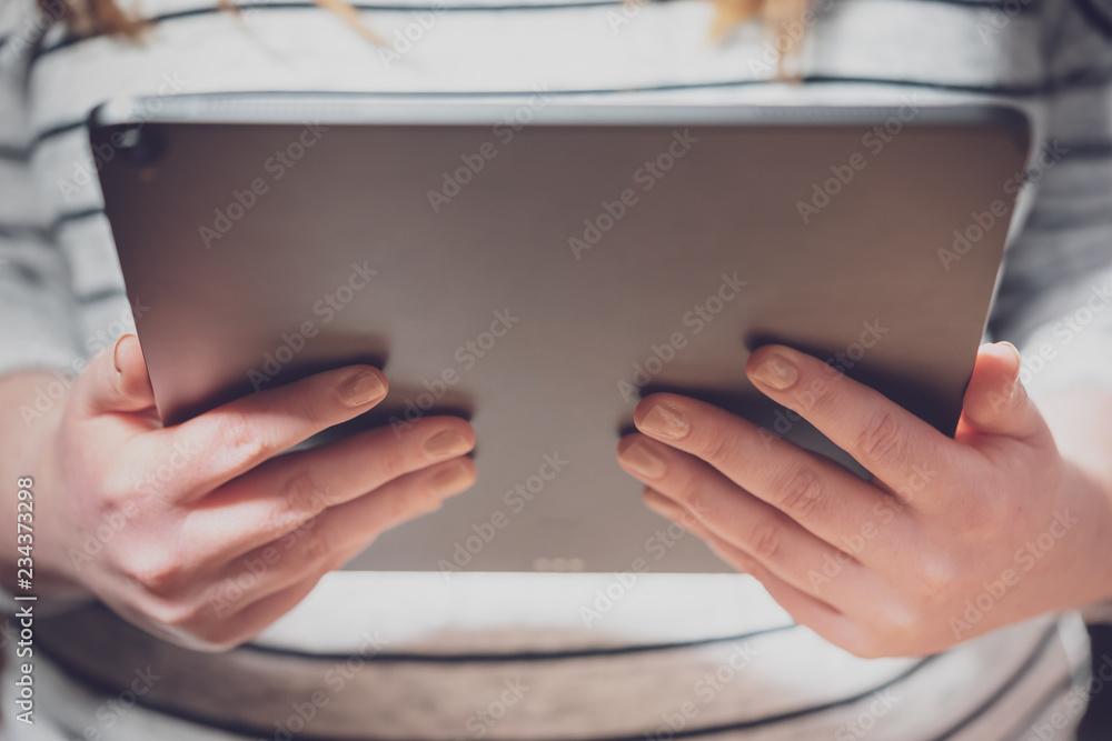 Woman using tablet computer with dramatic lighting and shallow depth of field. Blank screen with bright lighting for design mockups. Woman using tablet computer with dramatic lighting and shallow depth of field. Blank screen with bright lighting for design mockups.