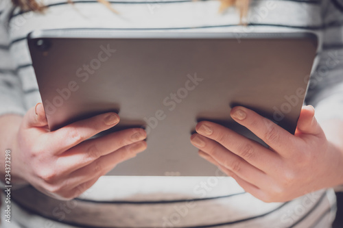Woman using tablet computer with dramatic lighting and shallow depth of field. Blank screen with bright lighting for design mockups.