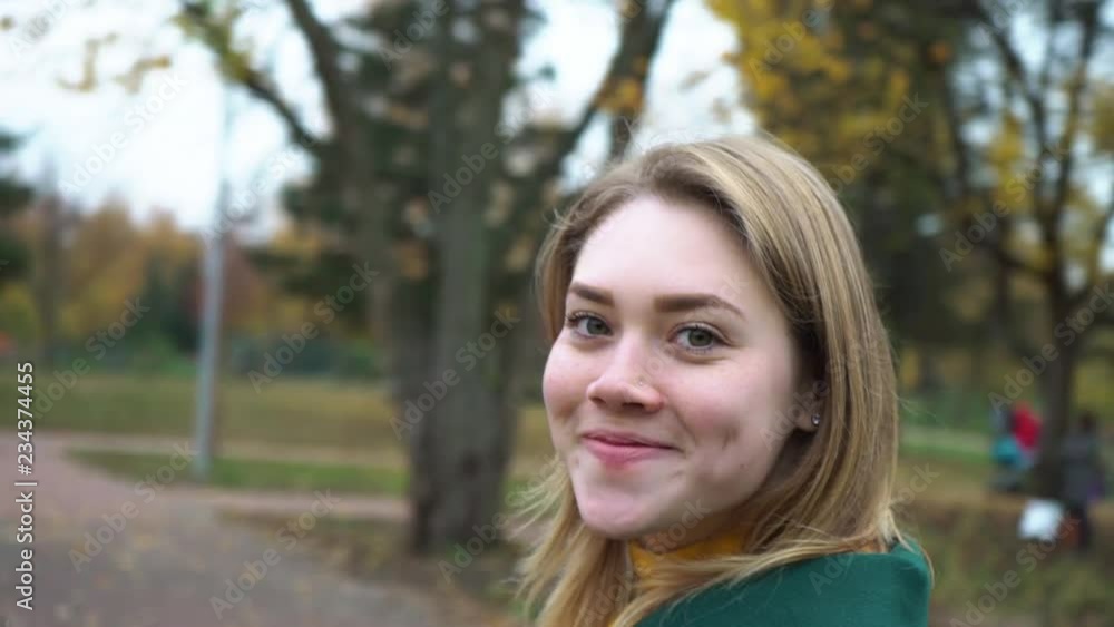 Autumn portrait of beautiful woman over yellow leaves while walking in the park in fall. The camera pans around the young woman. Girl is spinning. Blonde young girl in a green coat. Autumn portrait of beautiful woman over yellow leaves while walking in the park in fall. The camera pans around the young woman. Girl is spinning. Blonde young girl in a green coat.