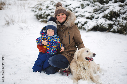 Beautiful mother and son playing with my dog in the snow. Golden Retriever
