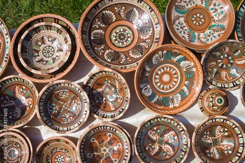 many handmade and handpainted ceramic clay plates with floral and abstract pattern in the sunshine