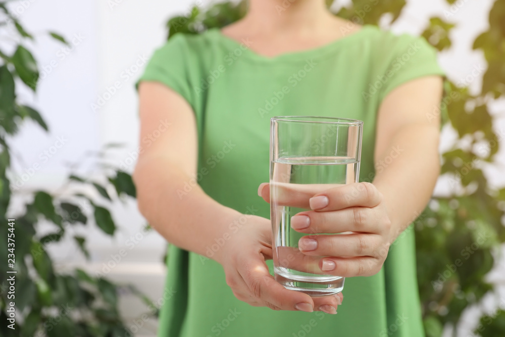Woman holding glass of fresh water indoors, closeup Woman holding glass of fresh water indoors, closeup