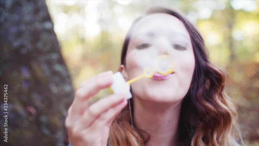 Portrait of woman blowing bubbles into the camera outdoor. Autumn forest Portrait of woman blowing bubbles into the camera outdoor. Autumn forest