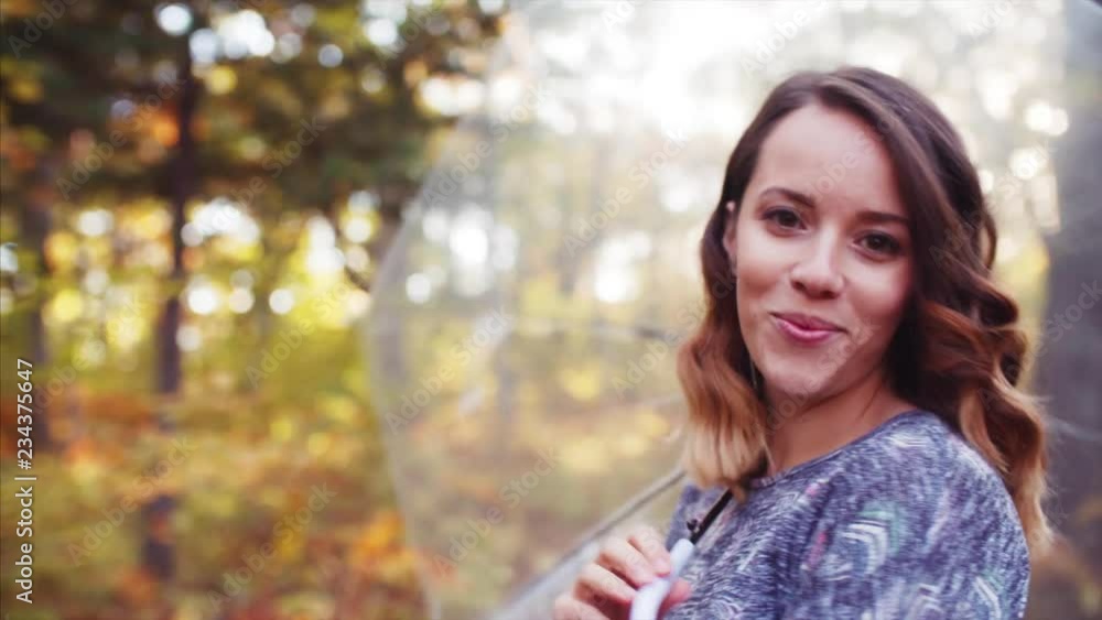 Portrait of young woman looking into camera, smiling, playing with umbrella