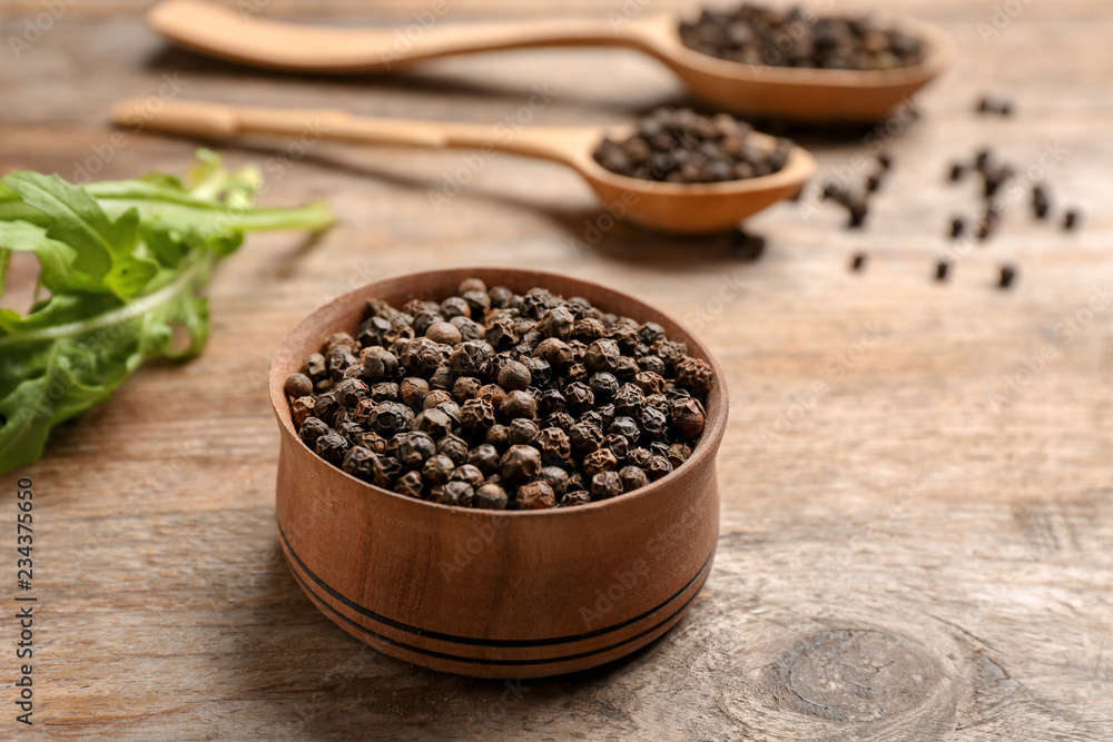 Bowl with black peppercorns on wooden table Bowl with black peppercorns on wooden table