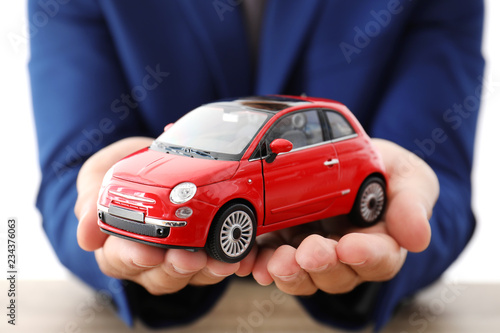 Insurance agent holding toy car over table, focus on hands