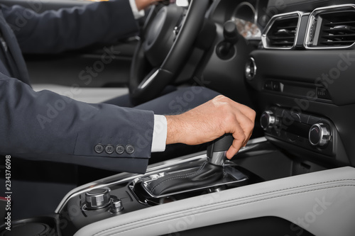 Man holding hand on gear lever in modern car, closeup