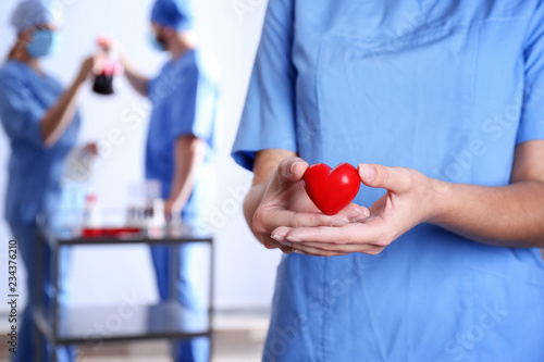 Doctor holding red heart at hospital, closeup. Donation day