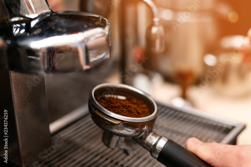 Male barista making espresso using professional coffee machine, closeup