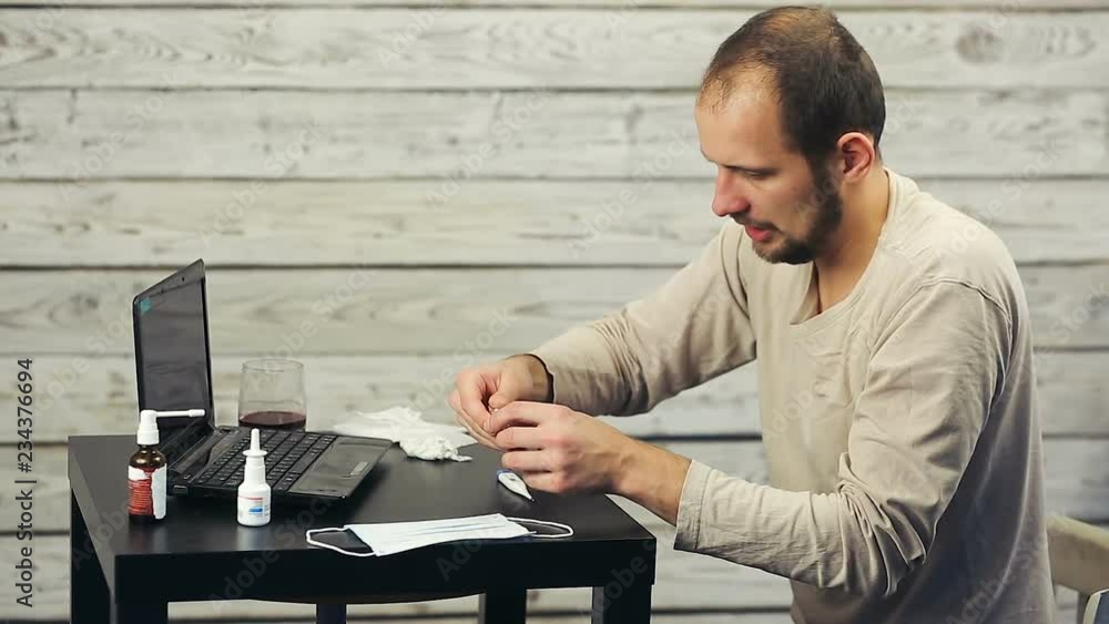 A bearded man works at the computer and coughs. A bearded man works at the computer and coughs.