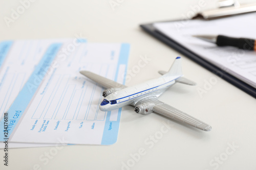 Toy plane and arrival card on white table. Travel insurance
