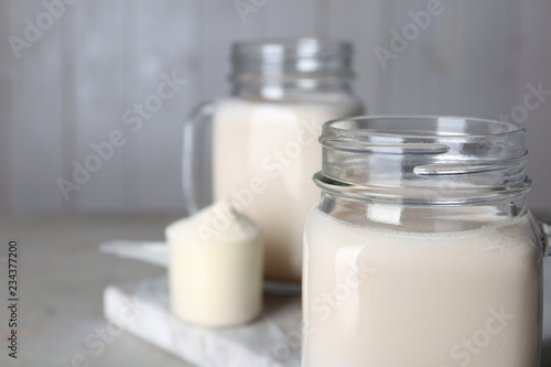 Mason jar with protein shake on table, closeup. Space for text
