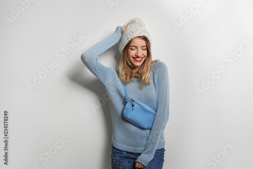Beautiful young woman in warm sweater with bag on white background