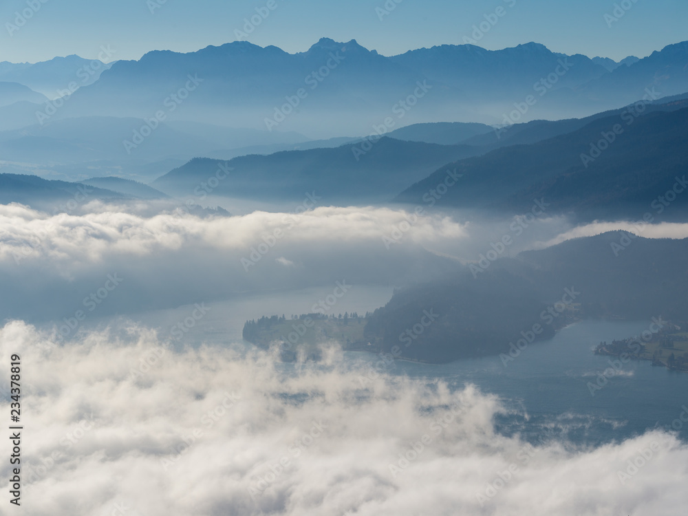 Panorama of beautiful low clouds over Lakes with blue mountains in background, trees in foreground
