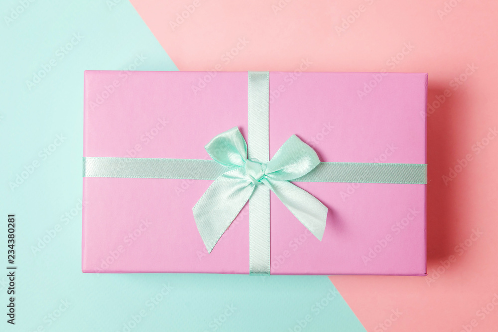 Small gift box wrapped pink and blue paper isolated on blue and pink pastel colorful trendy geometric background. Christmas New Year birthday valentine celebration present romantic concept Small gift box wrapped pink and blue paper isolated on blue and pink pastel colorful trendy geometric background. Christmas New Year birthday valentine celebration present romantic concept