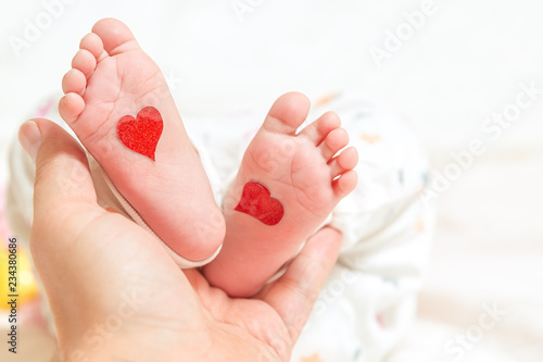 Wallpaper Mural Father holds a small leg of a newborn baby. hearts for parents day or valentines day Torontodigital.ca