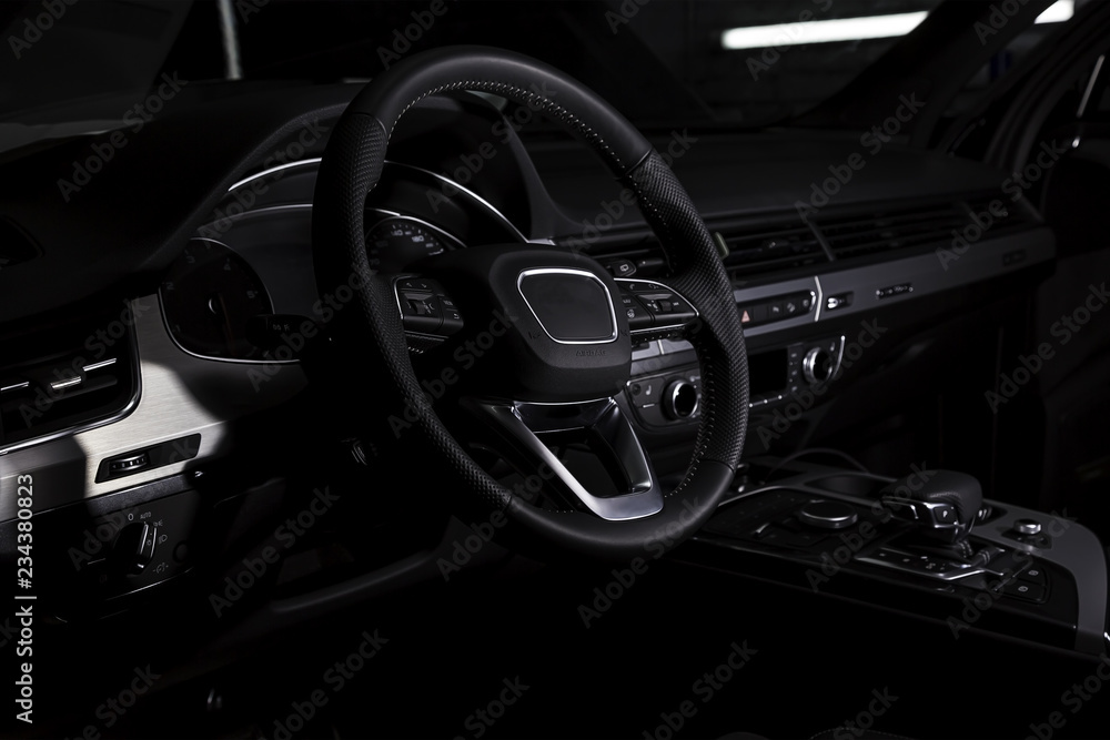 Interior of luxury suv car with black leather steering wheel and shift gear. Alcantara cockpit seats and doors. Black dashboard.
