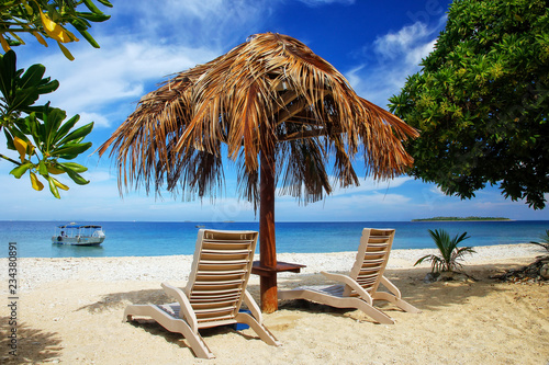 Sun chairs with thatched umbrella on a white sandy beach photo