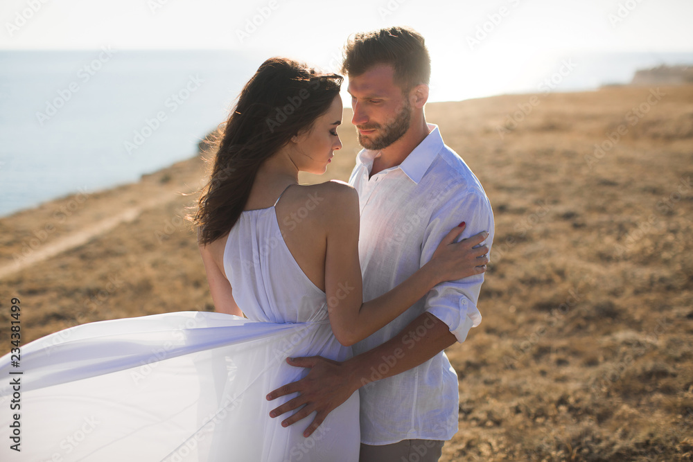 Beautiful young couple hugging in nature. People in white clothes.