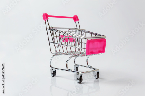 Small supermarket grocery push cart for shopping toy with wheels isolated on white background. Sale buy mall market shop consumer concept. Copy space