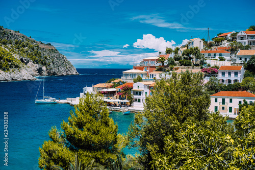 Assos village. Beautiful view to vivid colorful houses near blue turquoise colored transparent bay lagoon with yacht ship. Kefalonia, Greece photo