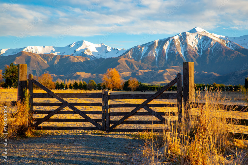 A closed wooden farm gate at the entrance to a farm in the high country below snowy mountains, Springfield, New Zealand	