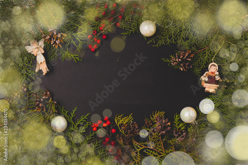 Merry Christmas and Happy New Year background. Christmas wreath with snow fir cones, xmas decorations . Flat lay. Copy space. Snow and light effect boke. Black background.