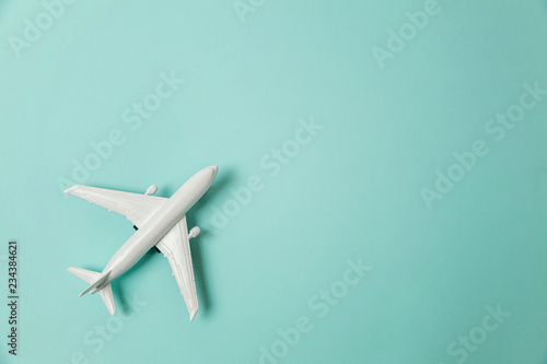 Simply flat lay design miniature toy model plane on blue pastel colorful paper trendy background. Travel by plane vacation summer weekend sea adventure trip journey ticket tour concept