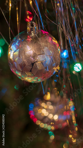 Brightly colored, cheery Christmas tree ornaments hung up with lights and tinsel
