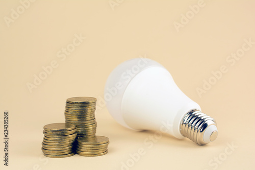 energy saving lamp and coins. energy bill , energy efficiency concept