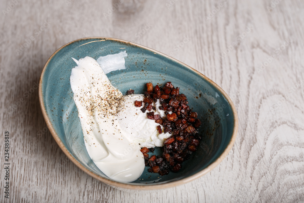 Fototapeta premium Boiled eggs with fried bacon and sour cream