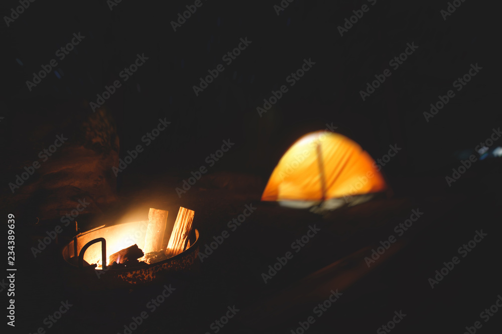 View of an orange tent under the night sky with a campfire in american campground, Yosemite National Park, California, United States