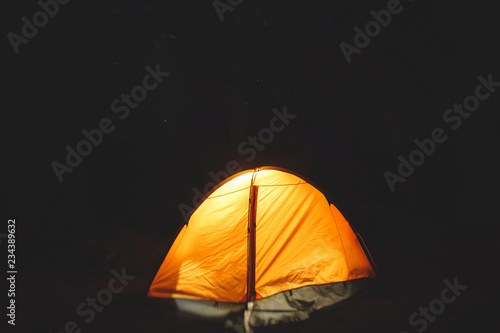 View of an orange tent under the night sky with a campfire in american campground, Yosemite National Park, California, United States