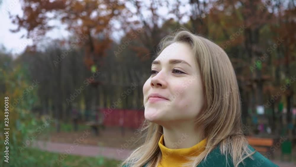 Autumn portrait of beautiful woman over yellow leaves while walking in the park in fall. Blonde young girl in a green coat. Positive emotions and happiness concept Autumn portrait of beautiful woman over yellow leaves while walking in the park in fall. Blonde young girl in a green coat. Positive emotions and happiness concept