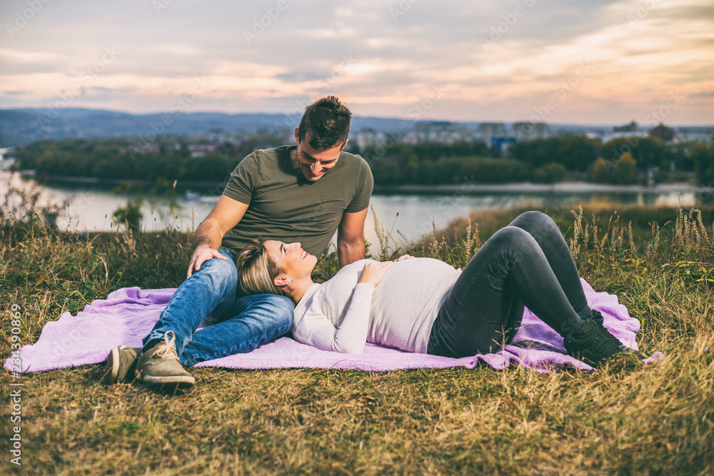 Husband and his pregnant wife enjoy spending time together outdoor.