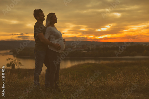 Husband and pregnant wife enjoy spending time together outdoor.