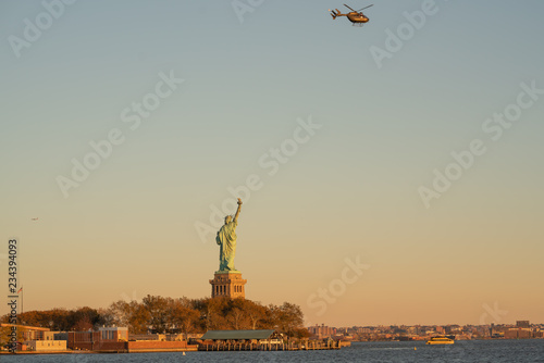 Helicopter flying over the Statue of Liberty just before Sunset