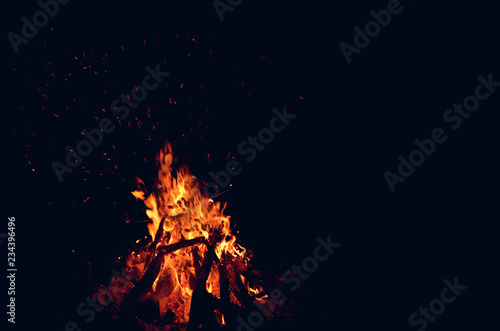 large fire scattering sparks in the dark on a black background