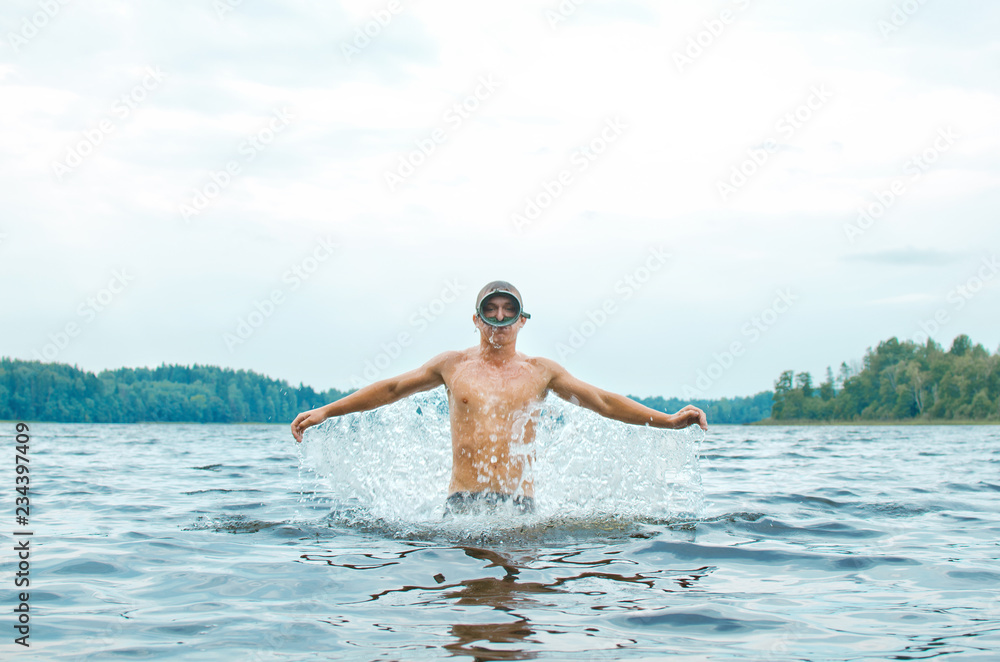 man in a diver mask jumps out of the water in a spray, bathing, summer vacation