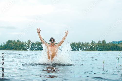 man in a diver mask jumps out of the water producing a lot of spray