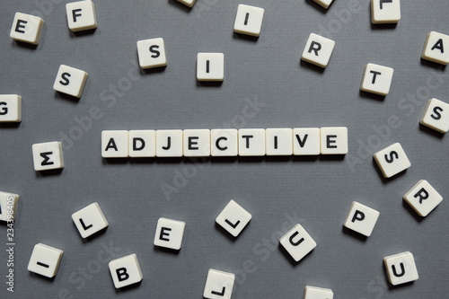 Adjective word made of square letter word on grey background.